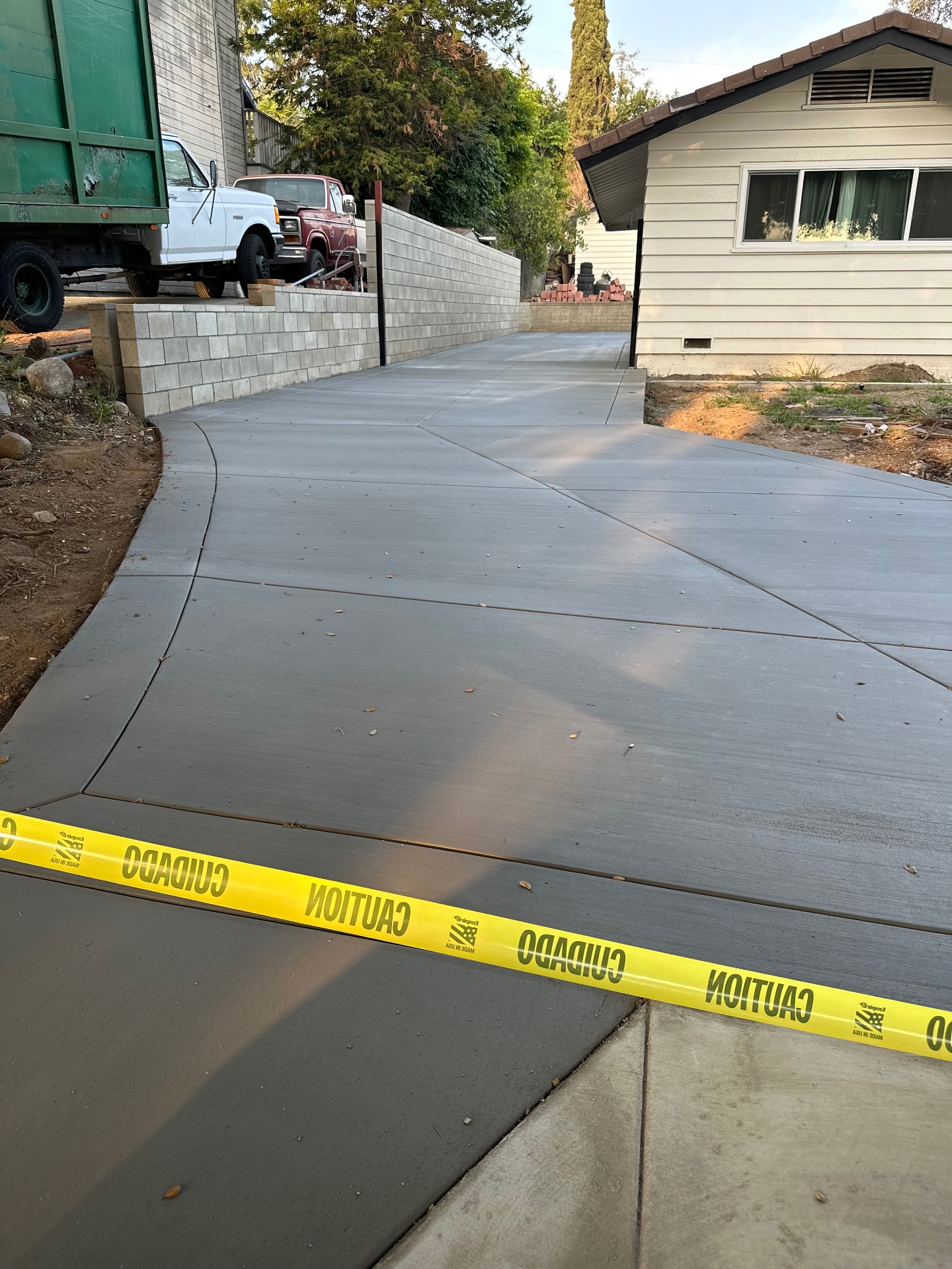 Newly poured concrete driveway alongside a finished block retaining wall on a completed D&M project