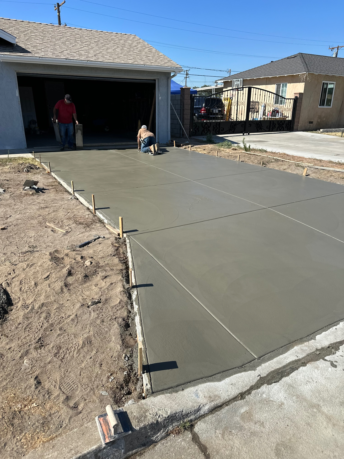 Freshly poured and finished concrete driveway in front of a residential garage on a completed D&M project