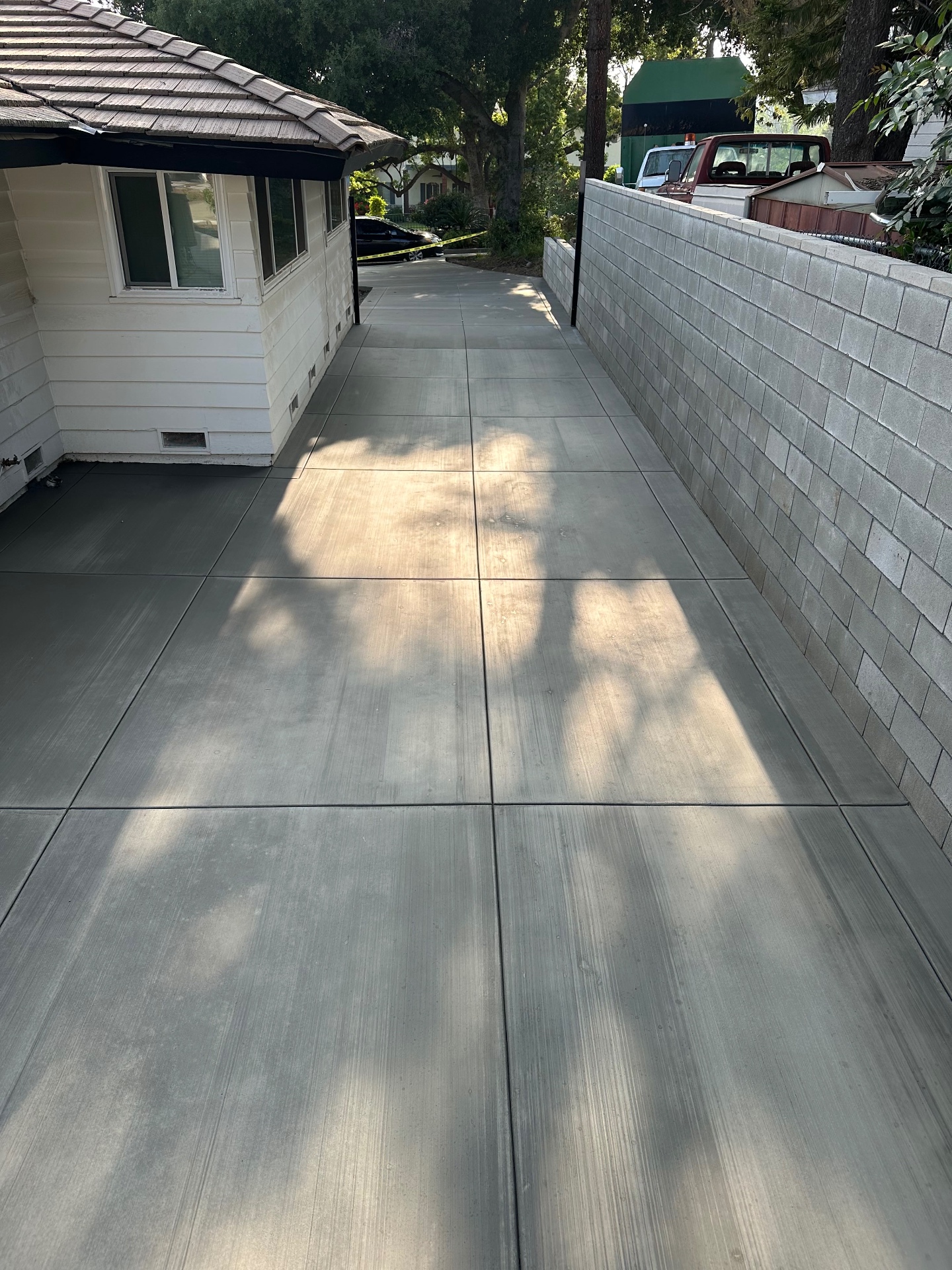 Completed concrete side-yard walkway alongside a finished block retaining wall at a residential D&M project