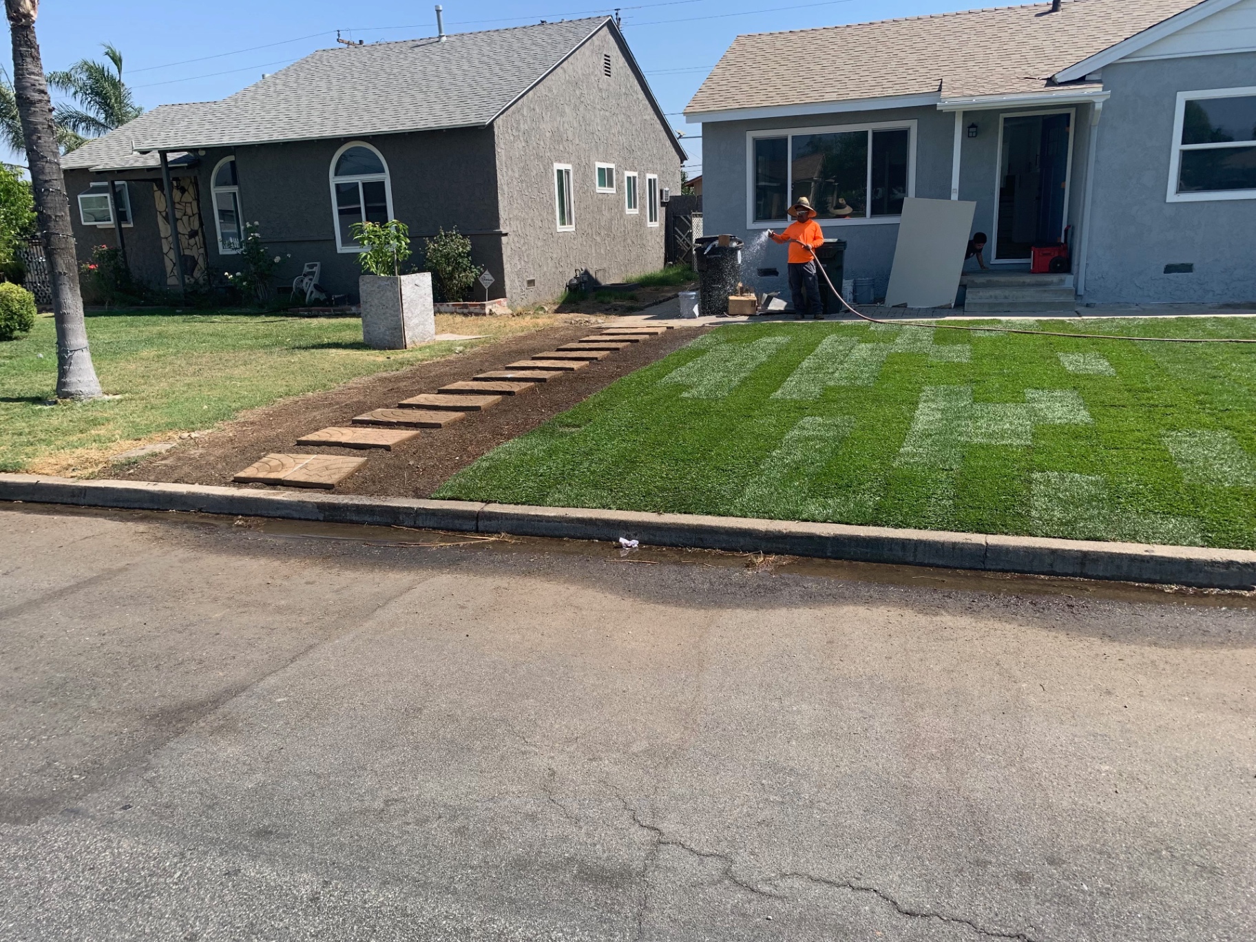 Completed front yard lawn installation with stepping-stone walkway and refreshed landscape beds at a residential project